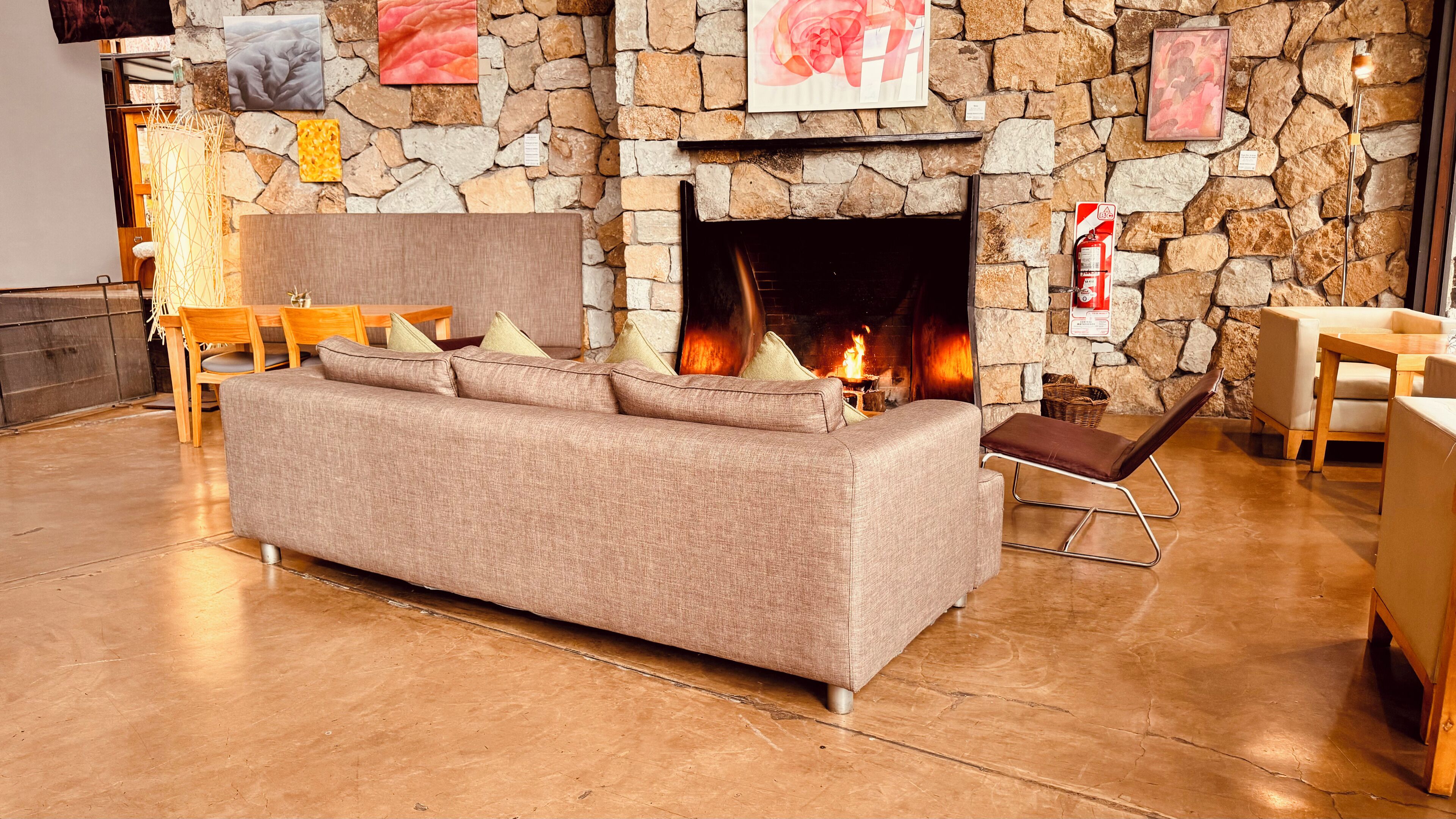 A cozy living room with a stone fireplace, a sofa, and a dining area.