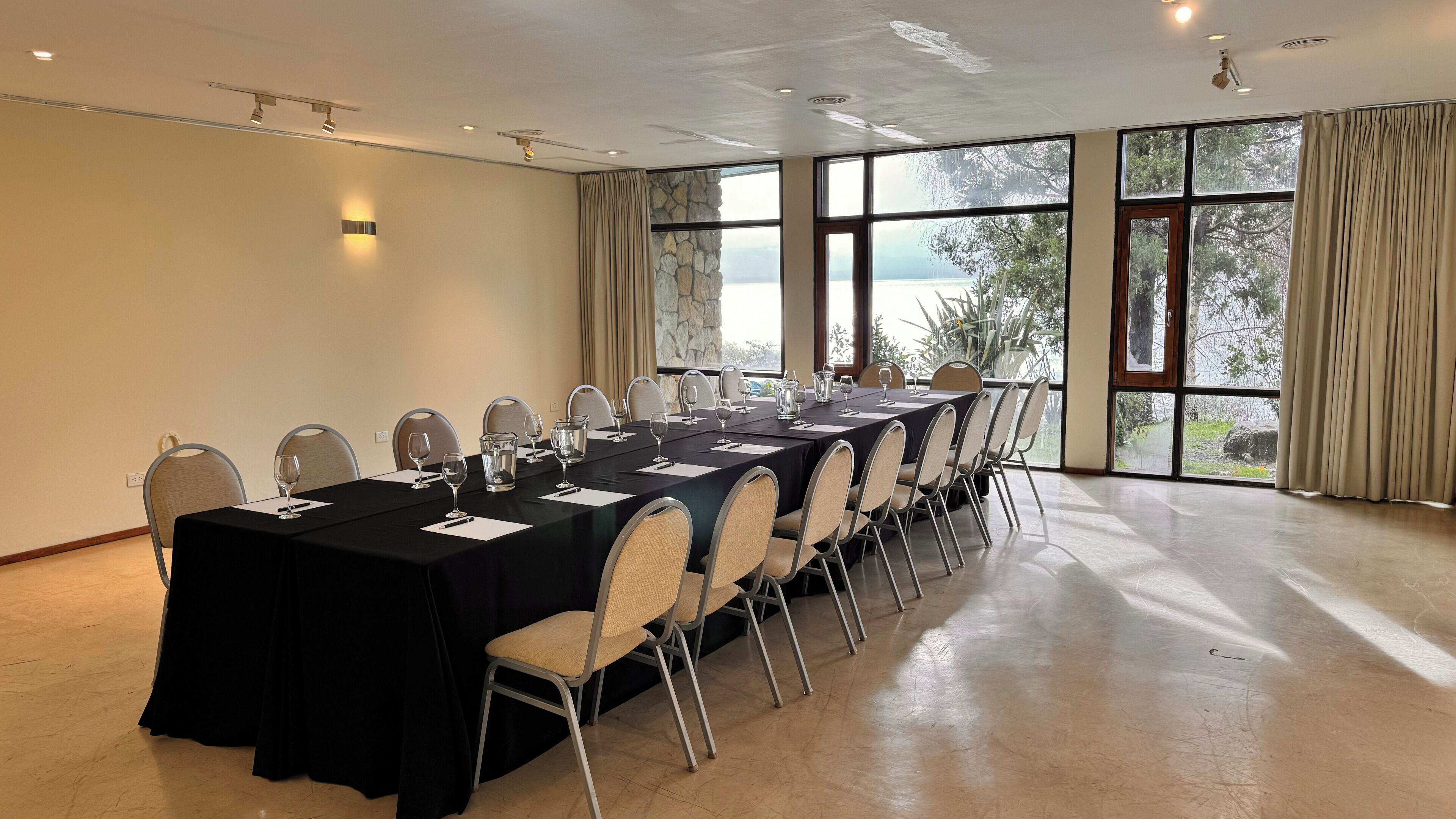Une salle de conférence dotée d’une longue table, de chaises et de grandes fenêtres offrant une vue dégagée.