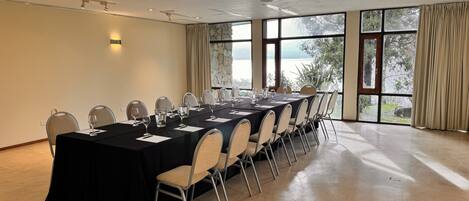 A conference room with a long table, chairs, and large windows with a view.