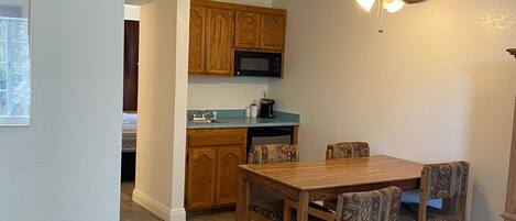 A modern kitchen with wooden cabinets, a microwave, and a ceiling fan.