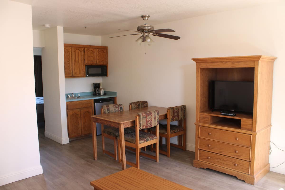 A compact living space with a dining area, kitchenette, and a TV stand.