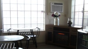 A kitchen with a dining table and chairs, a refrigerator, and a window with blinds. - Lodge on the River (Bullhead City)