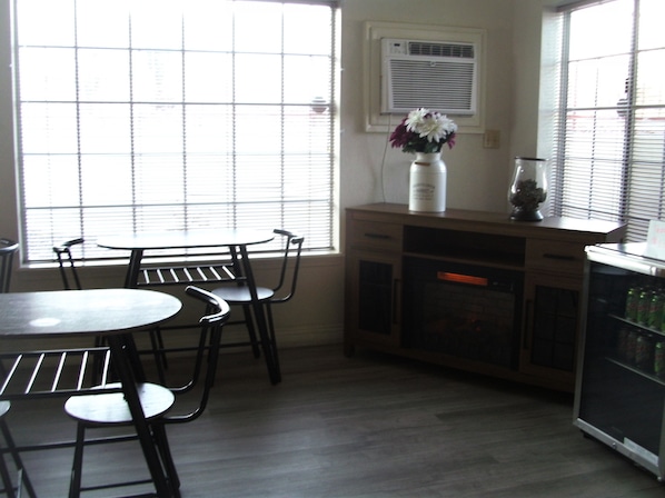 A kitchen with a dining table and chairs, a refrigerator, and a window with blinds.