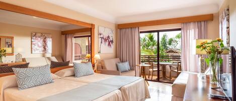 Habitación de hotel con dos camas, una zona de estar y un balcón con vistas al exterior.