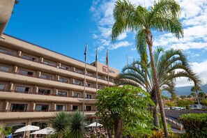 A hotel with multiple balconies, outdoor seating, and palm trees.
