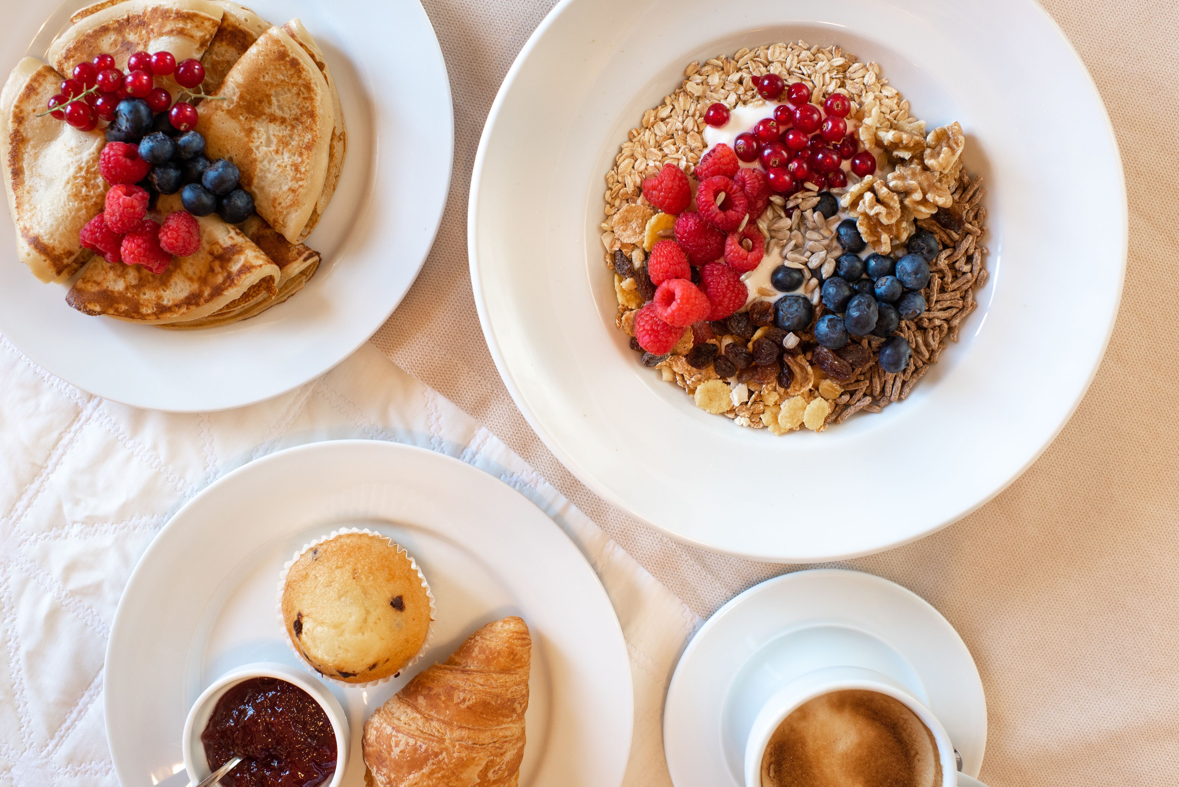 Tres platos de comida, un muffin y una taza de café sobre una mesa.