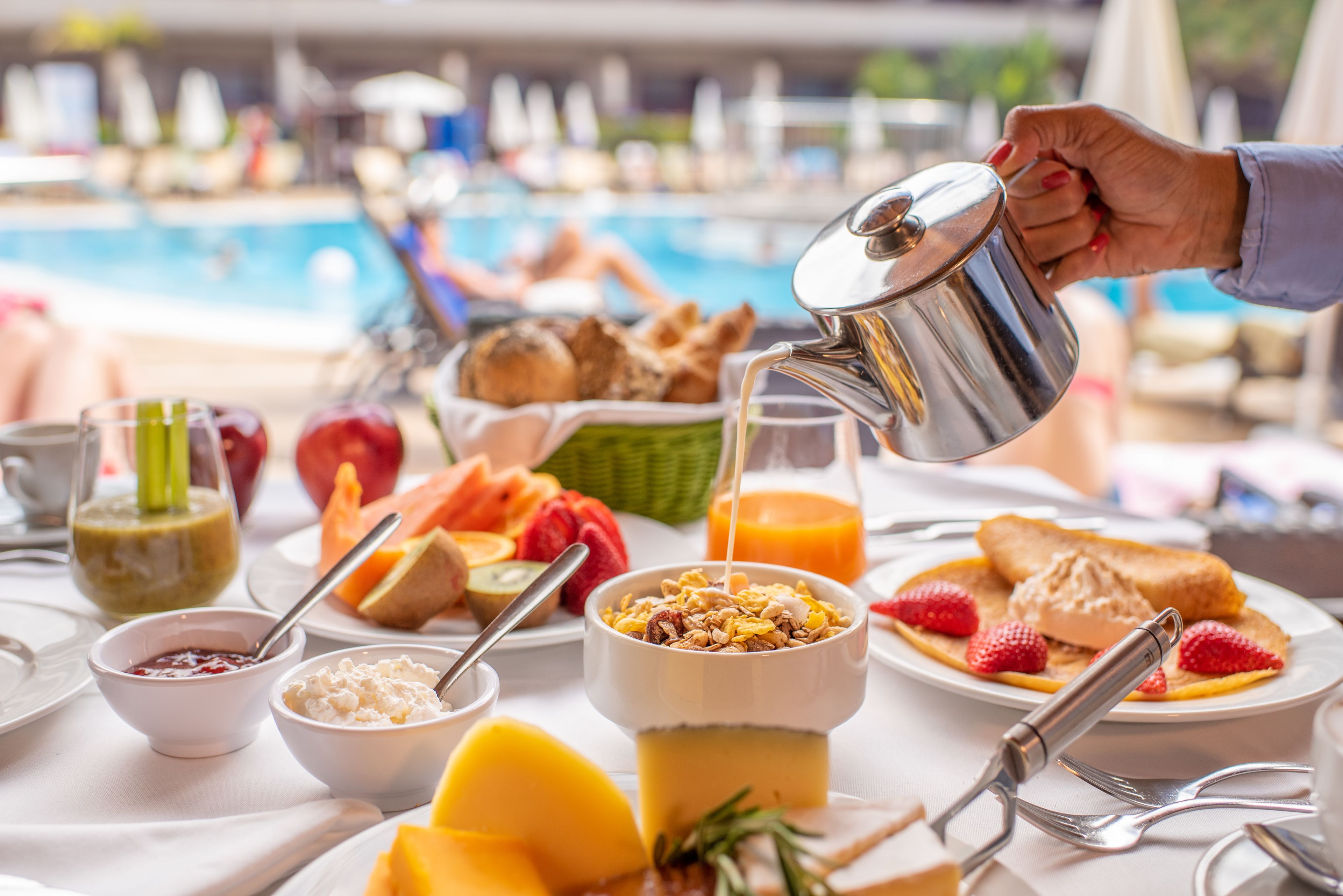 Un buffet de petit-déjeuner proposant une variété de plats, avec une piscine en arrière-plan.