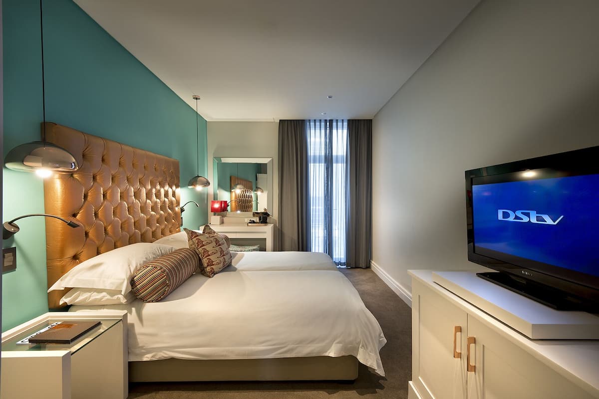 Ein modernes Hotelzimmer mit einem großen Bett, einem Fernseher und einem Badezimmer im Hintergrund.