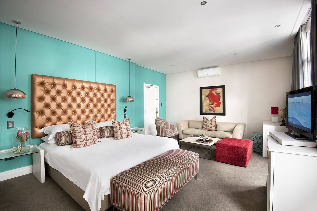 Ein modernes Hotelzimmer mit einem großen Bett, einer Couch, einem Couchtisch und einem Fernseher.