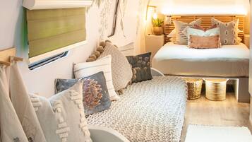 A cozy bedroom with a bed, pillows, a wall-mounted TV, and a ceiling mural.