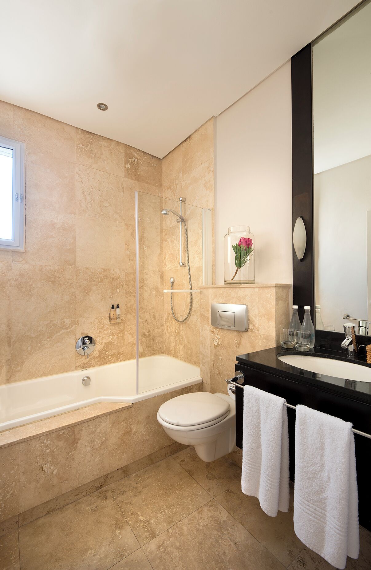 Ein modernes Badezimmer mit Badewanne, Dusche, Toilette und einem Waschtisch mit Spiegel.