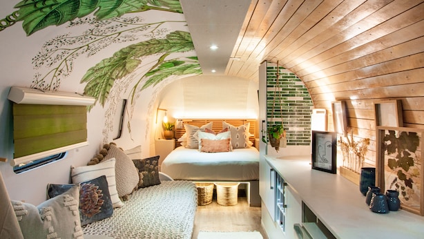 Une chambre confortable avec un lit, des oreillers et une fresque murale.