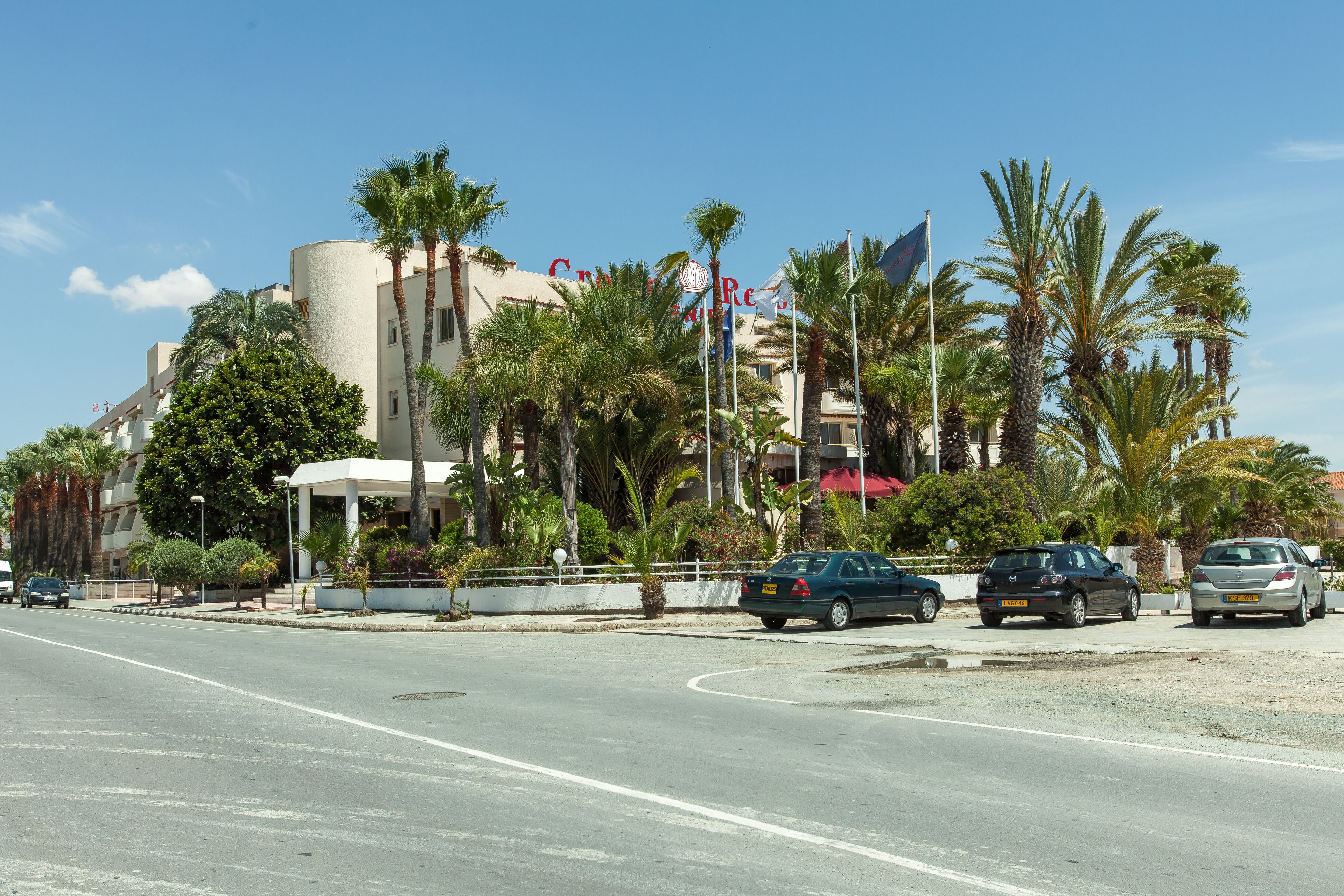 A hotel with a modern design, palm trees, and a clear blue sky.