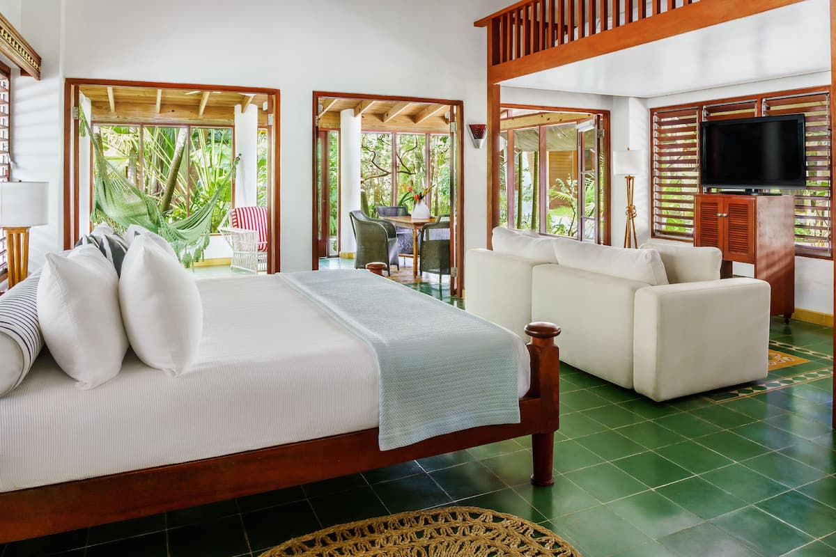 A spacious bedroom with a large bed, a sofa, and a television.