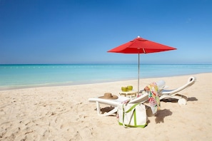 Een privéstrand, wit zand, parasols, strandlakens