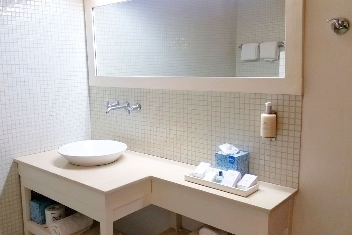 A bathroom with a white sink, mirror, and towel rack.