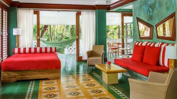 A hotel room with a bed, sofa, and chairs, a dining area, and a view of the outdoors.