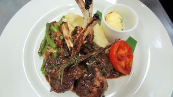 A plate of food with grilled meat, vegetables, and a small bowl of sauce.