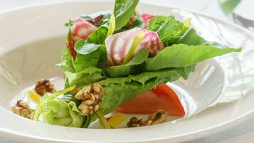 A plate of salad with lettuce, radishes, and walnuts.