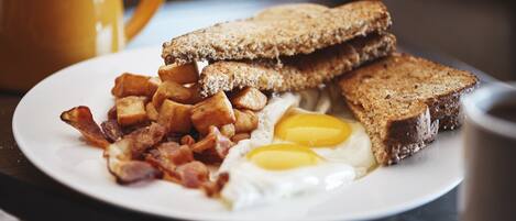 A plate with toast, bacon, eggs, and potatoes.