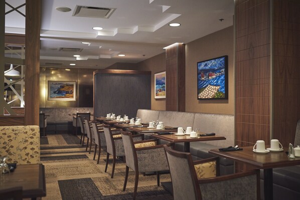 Un restaurant doté de nombreuses tables et de banquettes, avec de la vaisselle blanche et un décor intérieur moderne.