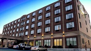 A multi-story hotel with a brick facade, multiple windows, and a parking area with several cars. - Capital Hotel (St. John's)