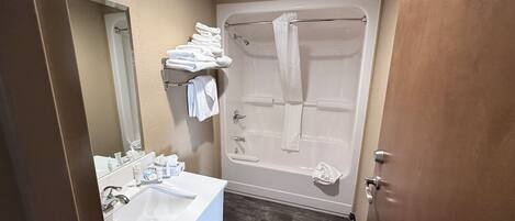 Une salle de bain équipée d’un lavabo, d’un miroir, d’un porte-serviettes et d’une baignoire.