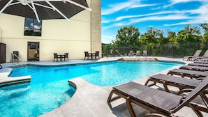 A swimming pool with lounge chairs, a covered seating area, and a view of trees and a fence. - Grand Oaks Hotel (Branson)