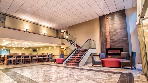 A spacious lobby with a central staircase, seating area, and a fireplace. - Grand Oaks Hotel (Branson)