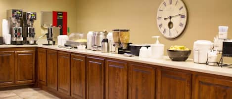 Una cocina de hotel con un reloj, cafeteras y dispensadores de alimentos.