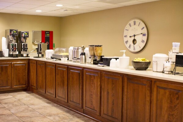A hotel kitchen with a clock, coffee machines, and food dispensers. - Grand Oaks Hotel (Branson)