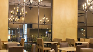 A restaurant with multiple tables and chairs, large windows, and chandeliers. - Grand Oaks Hotel (Branson)