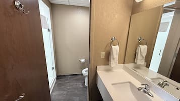 Un bagno con un lavandino bianco, uno specchio e un porta asciugamani.