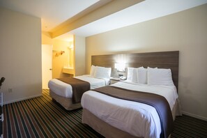 A hotel room with two beds, a striped carpet, and a wooden headboard.