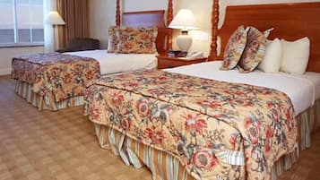 Camera d'albergo con due letti, una testiera in legno, un comodino con una lampada e una finestra con tende.