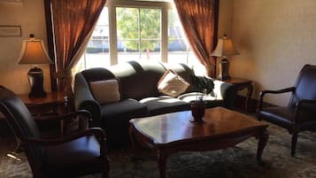 A cozy living room with a sofa, two armchairs, a coffee table, and a window with curtains.