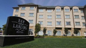 Une enseigne d’hôtel indiquant « Bay Landing Hotel », avec un immeuble à plusieurs étages en arrière-plan.
