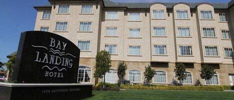 A hotel sign for Bay Landing Hotel with a multi-story building in the background.