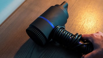 A cylindrical object with a blue stripe, a coiled cable, and a hand holding it.