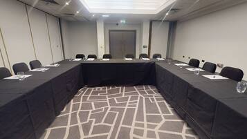 A conference room with a long table, chairs, and a patterned carpet.