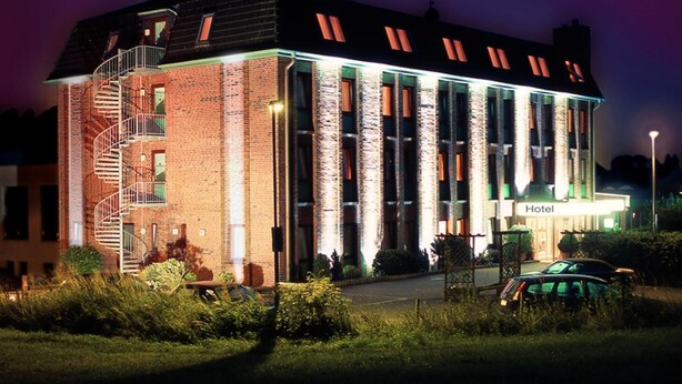 A hotel with a brick facade, large windows, and a spiral staircase. - Entrée Hotel Glinde (Glinde)