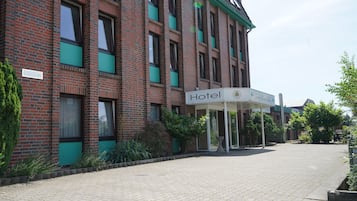 A hotel with a brick facade, a covered entrance, and a paved walkway.