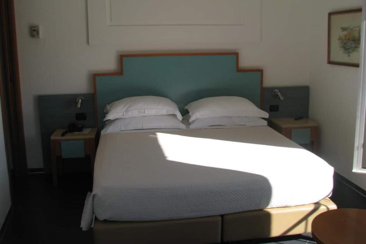 A neatly made bed with a wooden headboard, two bedside tables with lamps, and a framed picture on the wall.