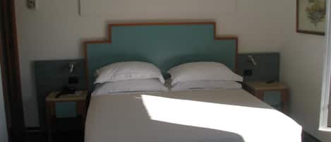 A neatly made bed with a wooden headboard, two bedside tables with lamps, and a framed picture on the wall.