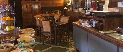 A cozy restaurant with wooden furniture, a bar area, and a variety of bottles on shelves.