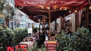 An outdoor café with red umbrellas, checkered tablecloths, and outdoor seating.