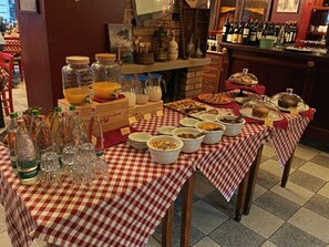A buffet table with various food items and condiments, surrounded by bottles and glasses. - Hotel Chelsea (Turin)