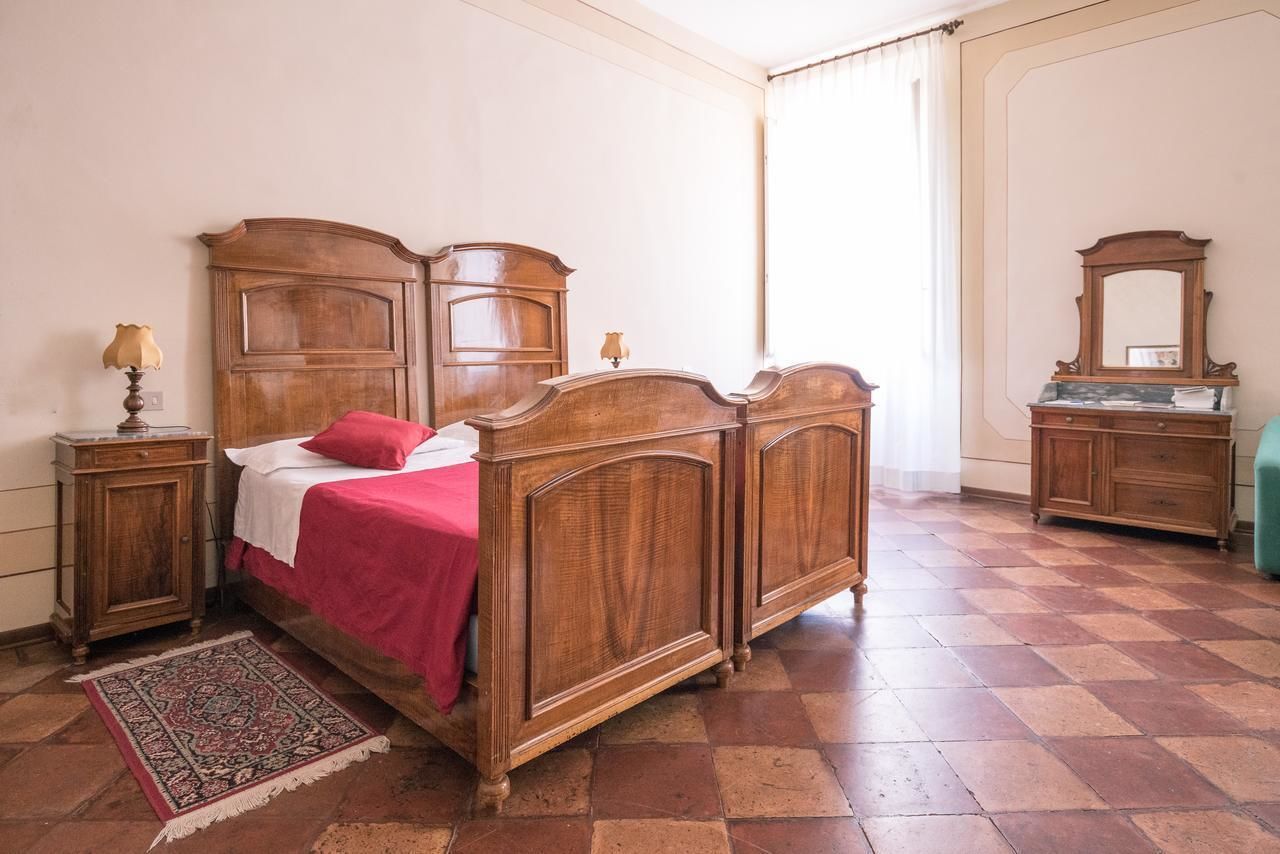 A traditional bedroom with a four-poster bed, a wooden nightstand, a dresser, and a mirror.
