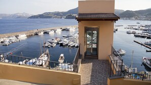 A marina with boats docked, a building with a balcony, and a mountainous backdrop. - Hotel A' Pinnata (Lipari)