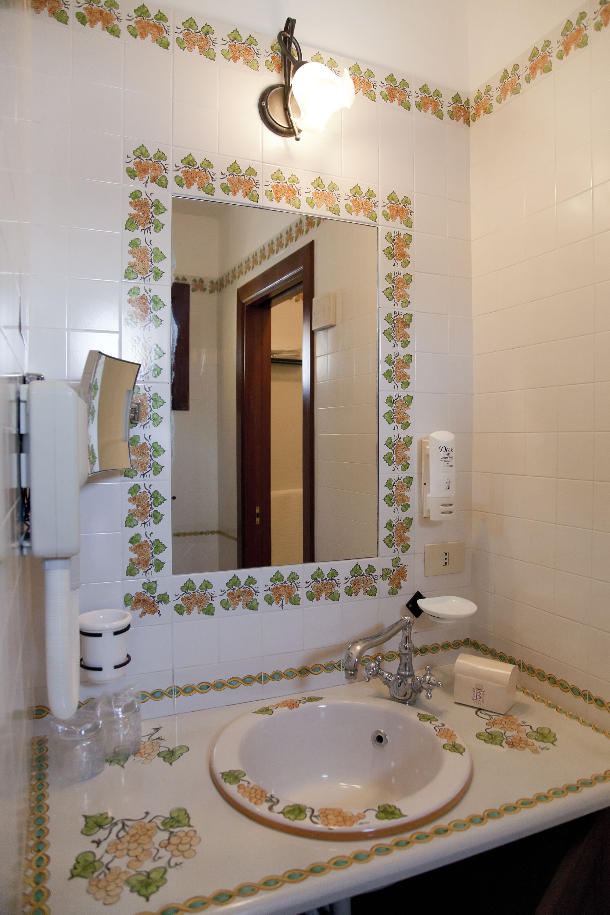 A bathroom with a white sink, a mirror, and a hand soap dispenser.